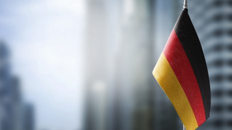 Deutsches Fläggchen vor grauer verschwommener Stadtsilhouette